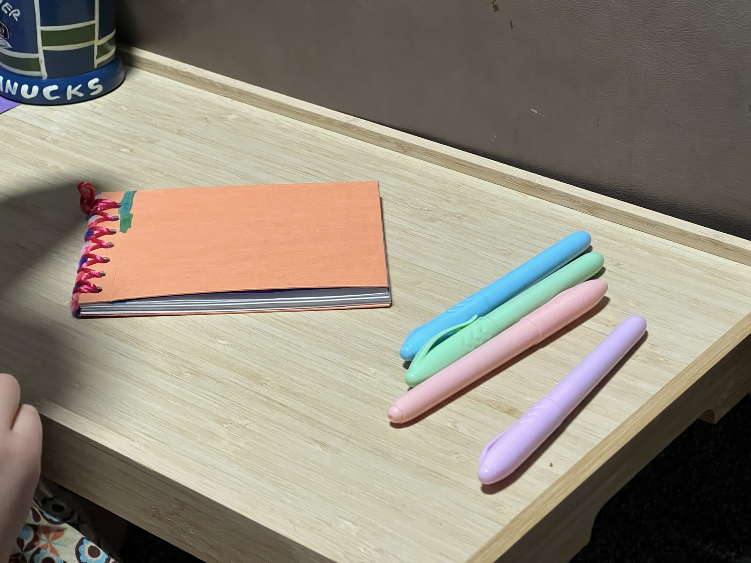 A small table with some markers on top along with a custom bound sketchbook