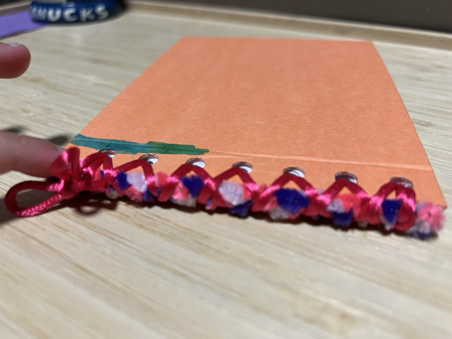 Photo of the spine of the custom bound sketchbook. It had an embedded pipe cleaner french braid in the binding