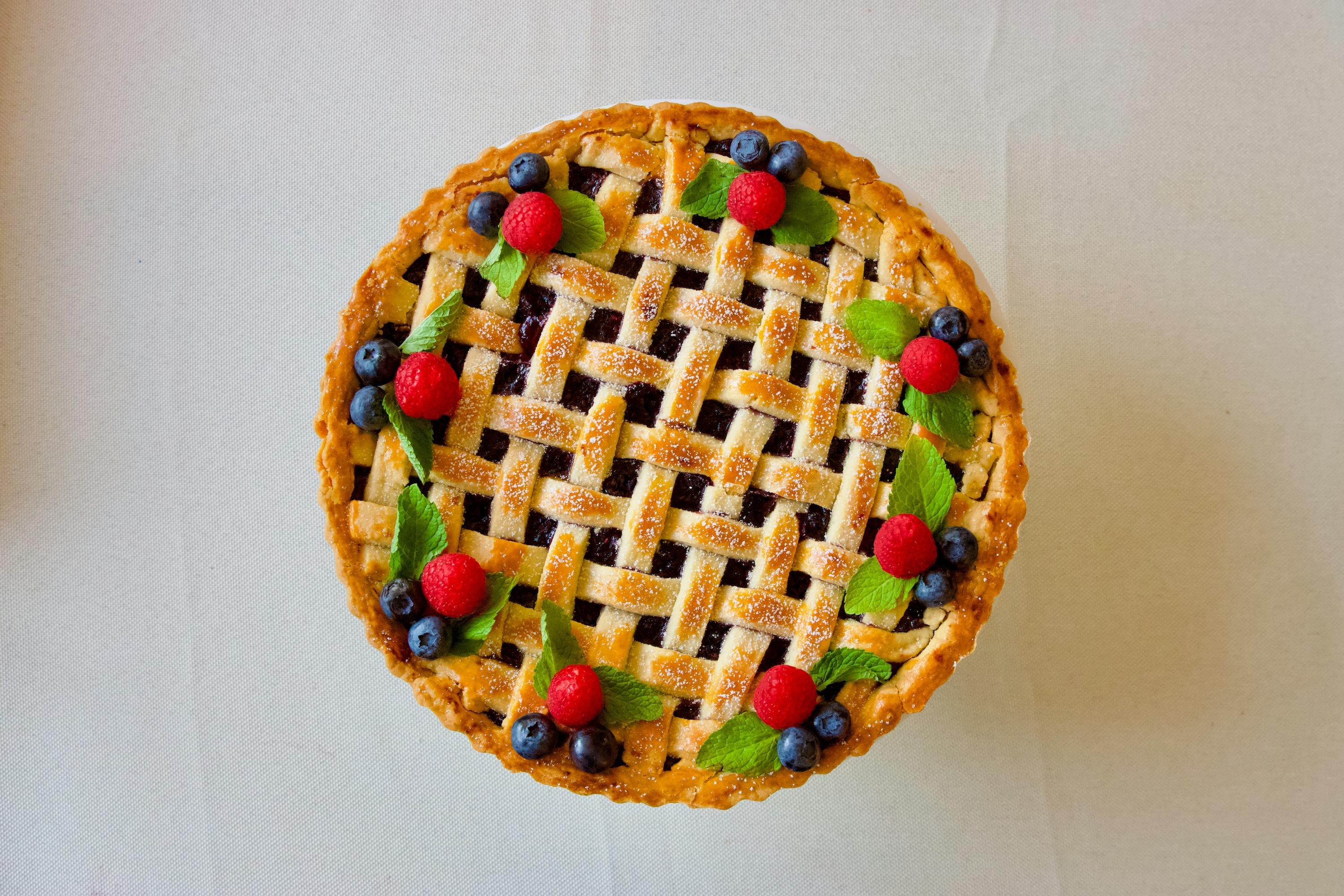 A photograph of a berry flavored pie with raspberries and blueberries for garnishes. Photo by Tuğçe Ertaş Al on Unsplash.
